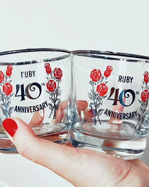 Close up of two rocks glasses held in hand against white background.