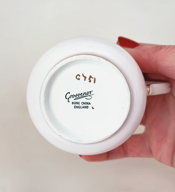 Close up of bottom of cup showing stamp "Grosvenor Bone China England, G751". White background.