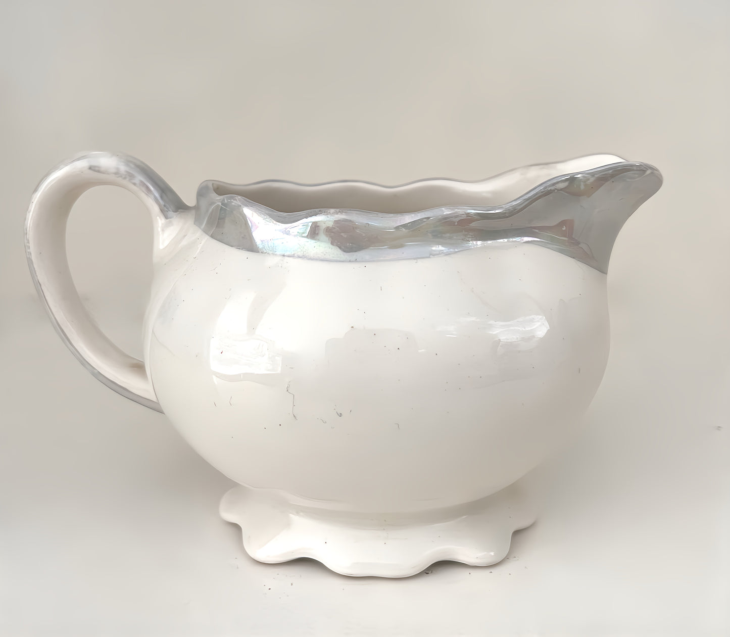 Close up of backside of creamer (no decorative design). White background.