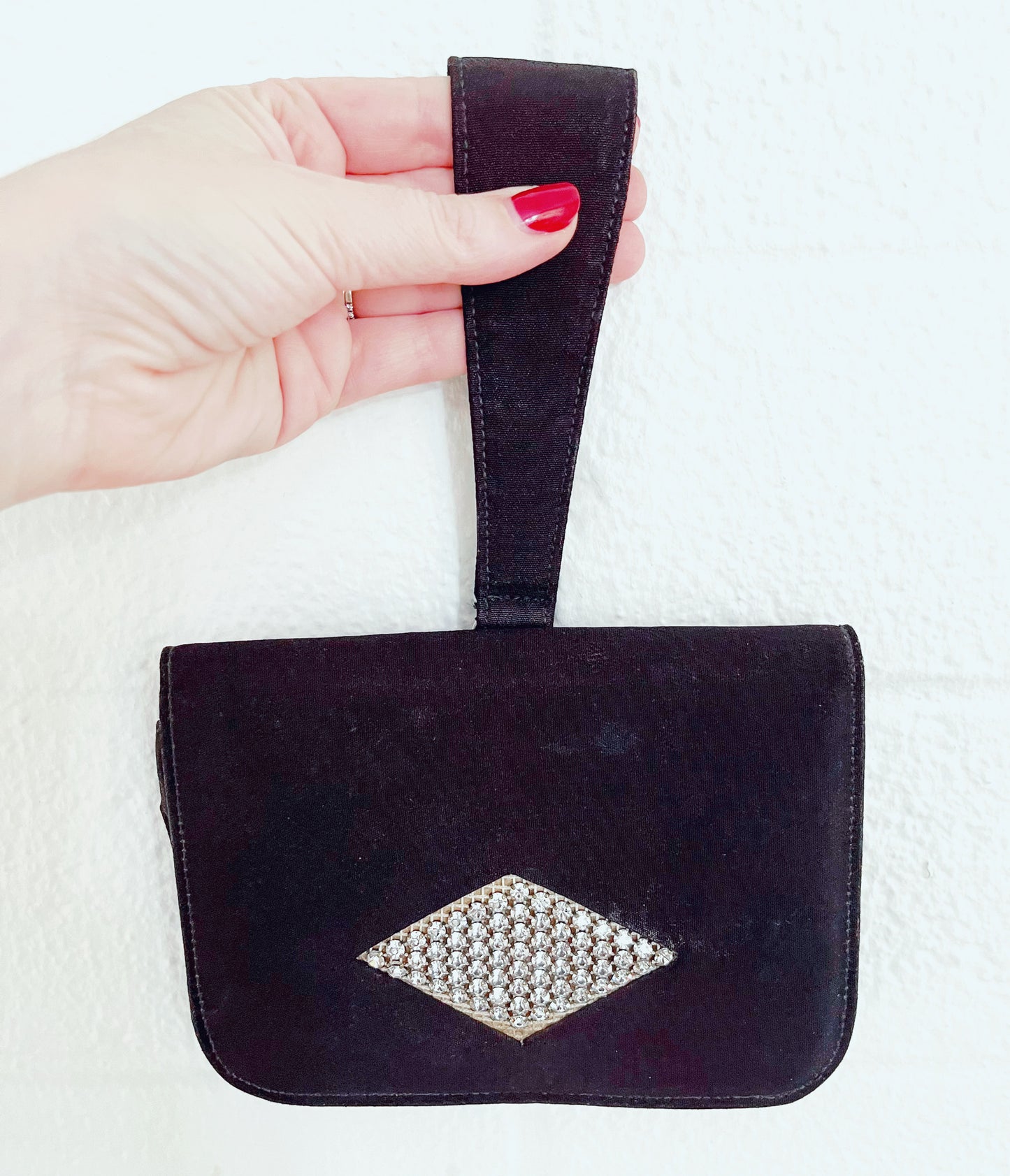 Image of bag being held up by strap against white background.