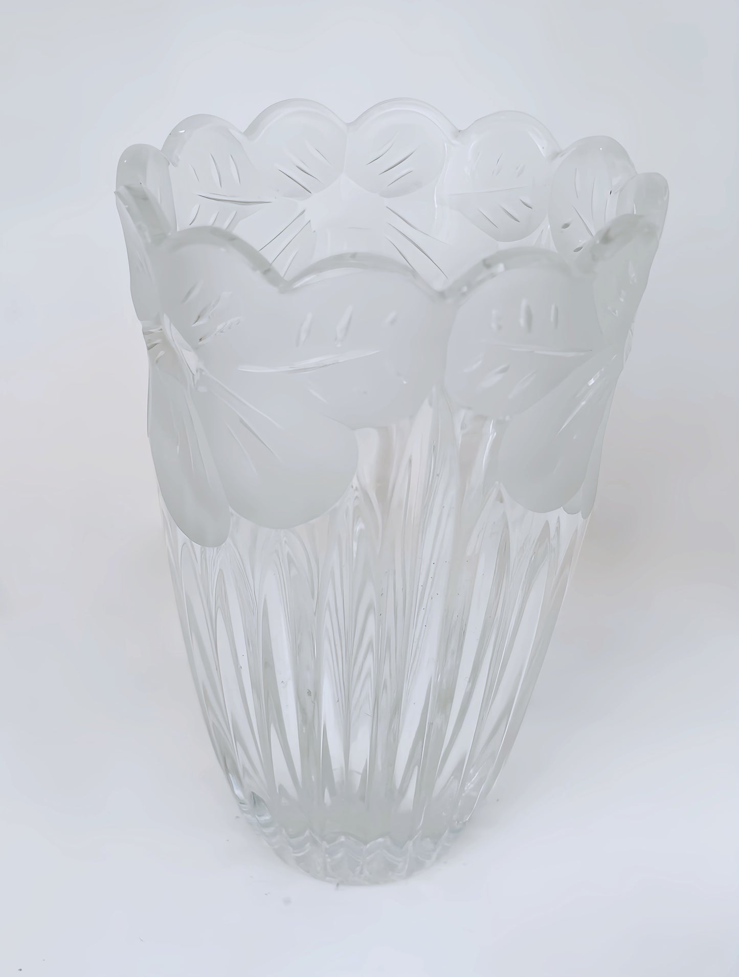 Close up of vase displaying etched flower motif along brim. White background.