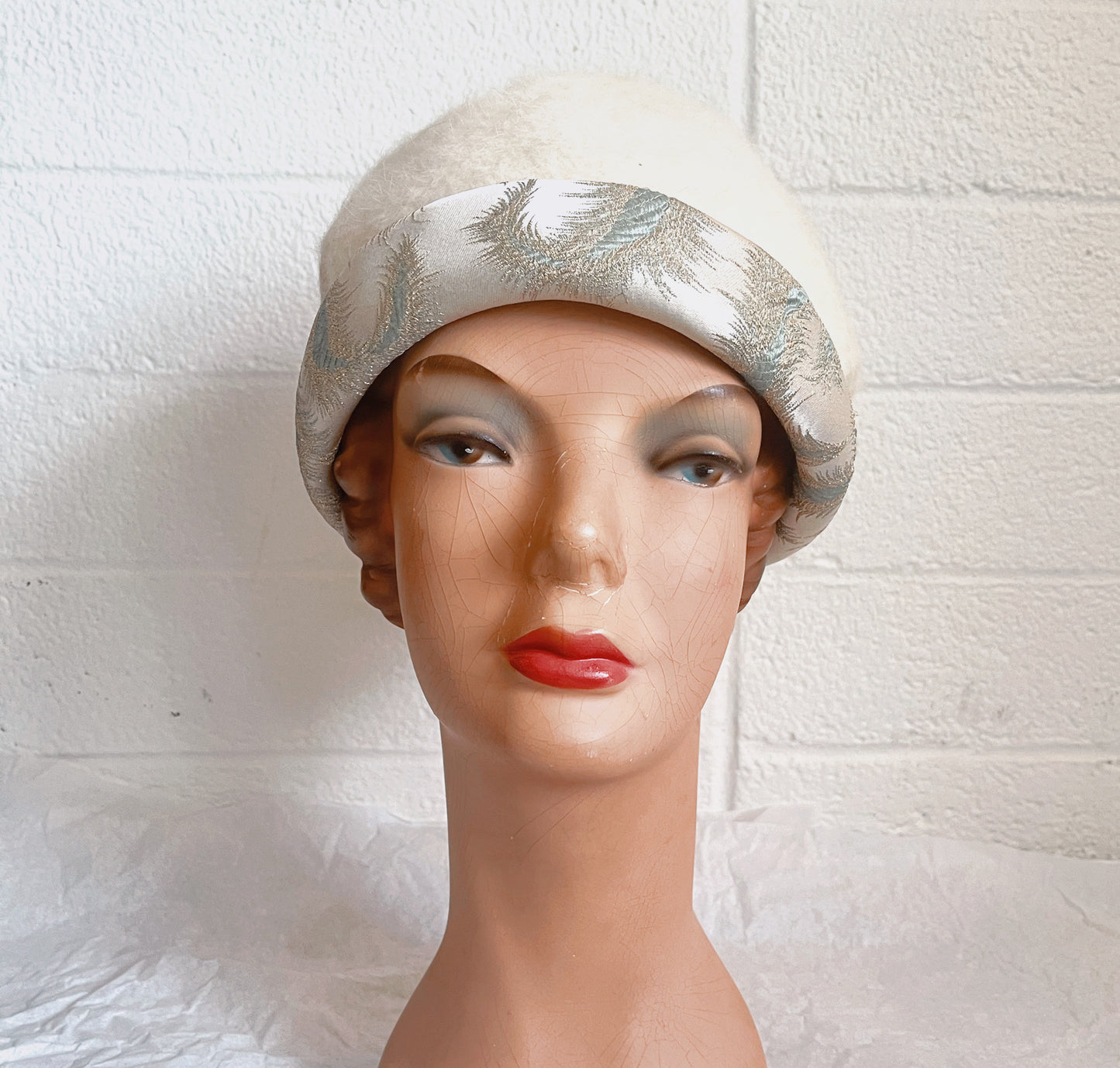 Image of hat on mannequin head. Shown against white brick background.