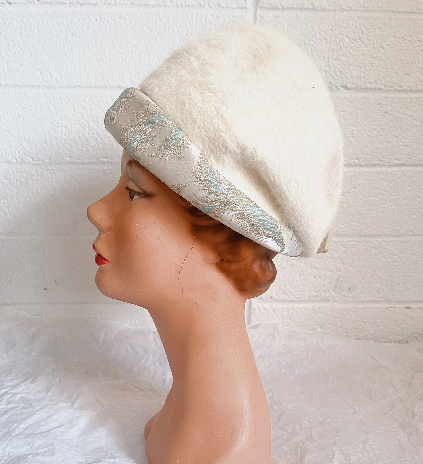 Side view image of hat on mannequin head. Shown against white brick background.