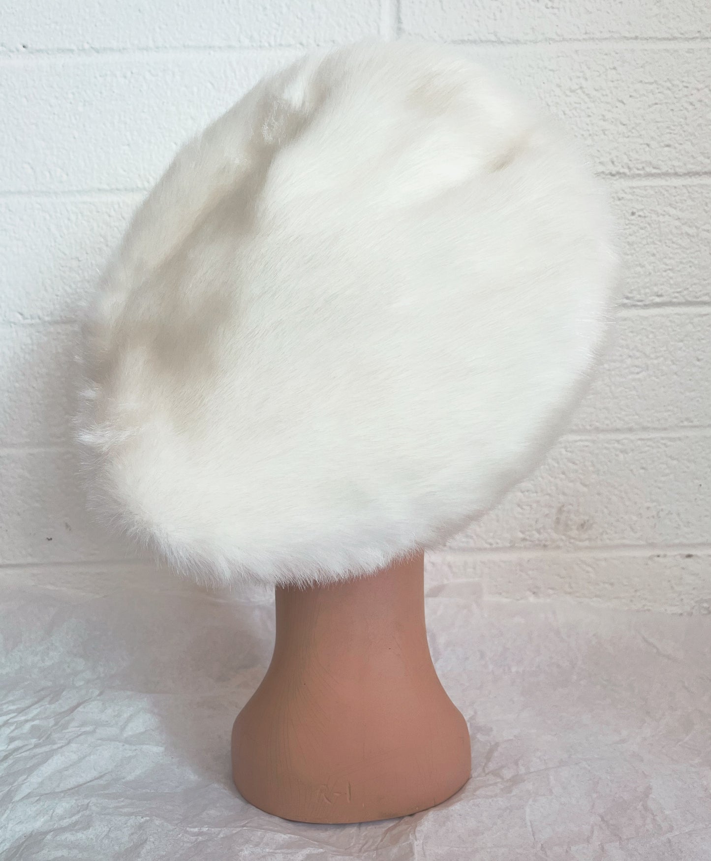 Back view image of vintage mannequin head wearing white hat with white background.