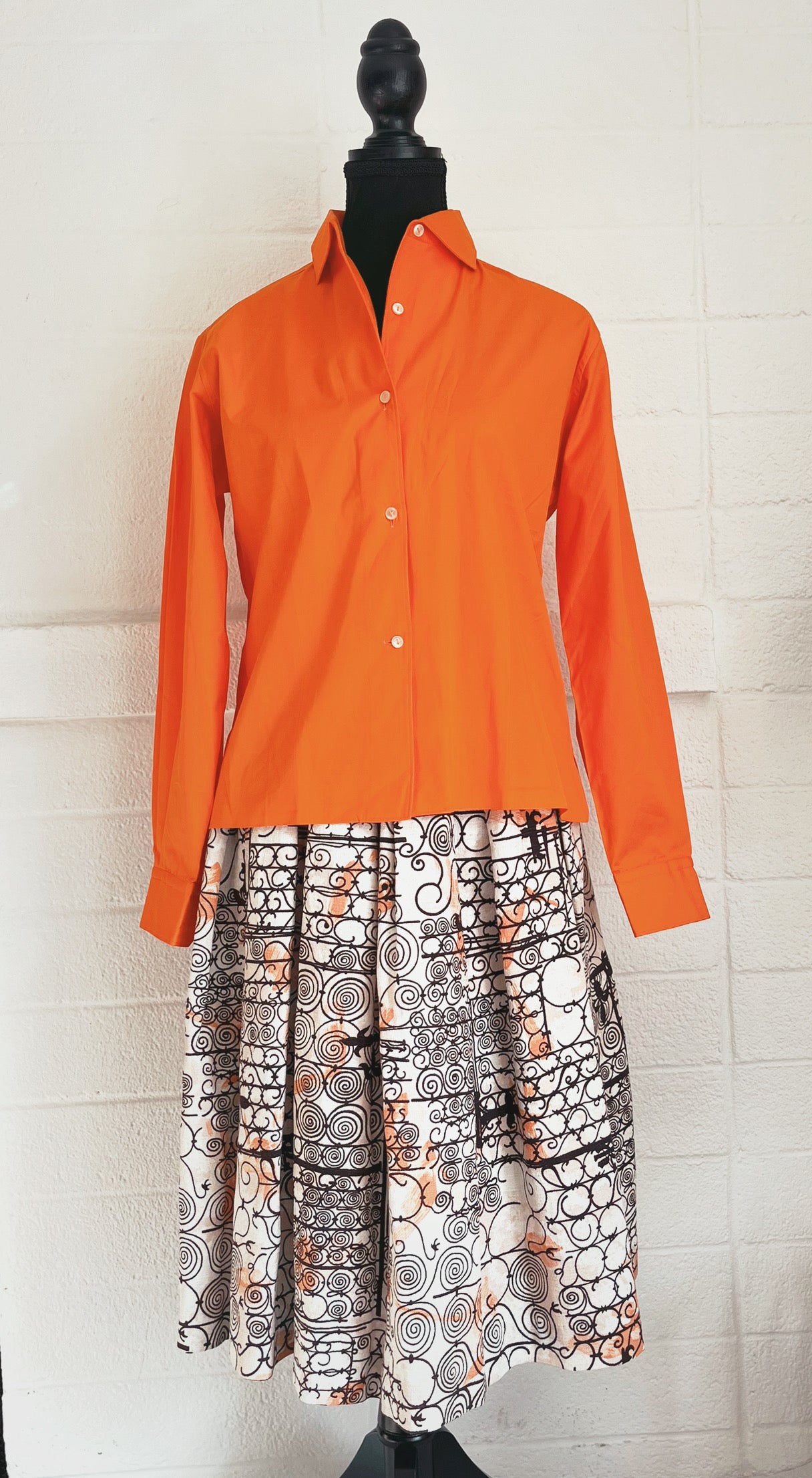 Image of skirt modelled on dressform with orange blouse untucked. White background.
