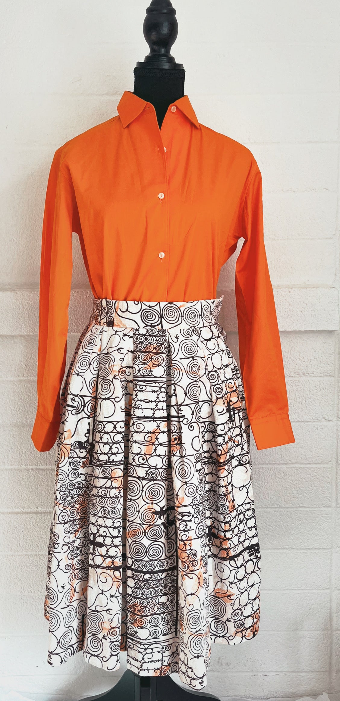 Image of skirt modelled on dressform with orange blouse. White background.