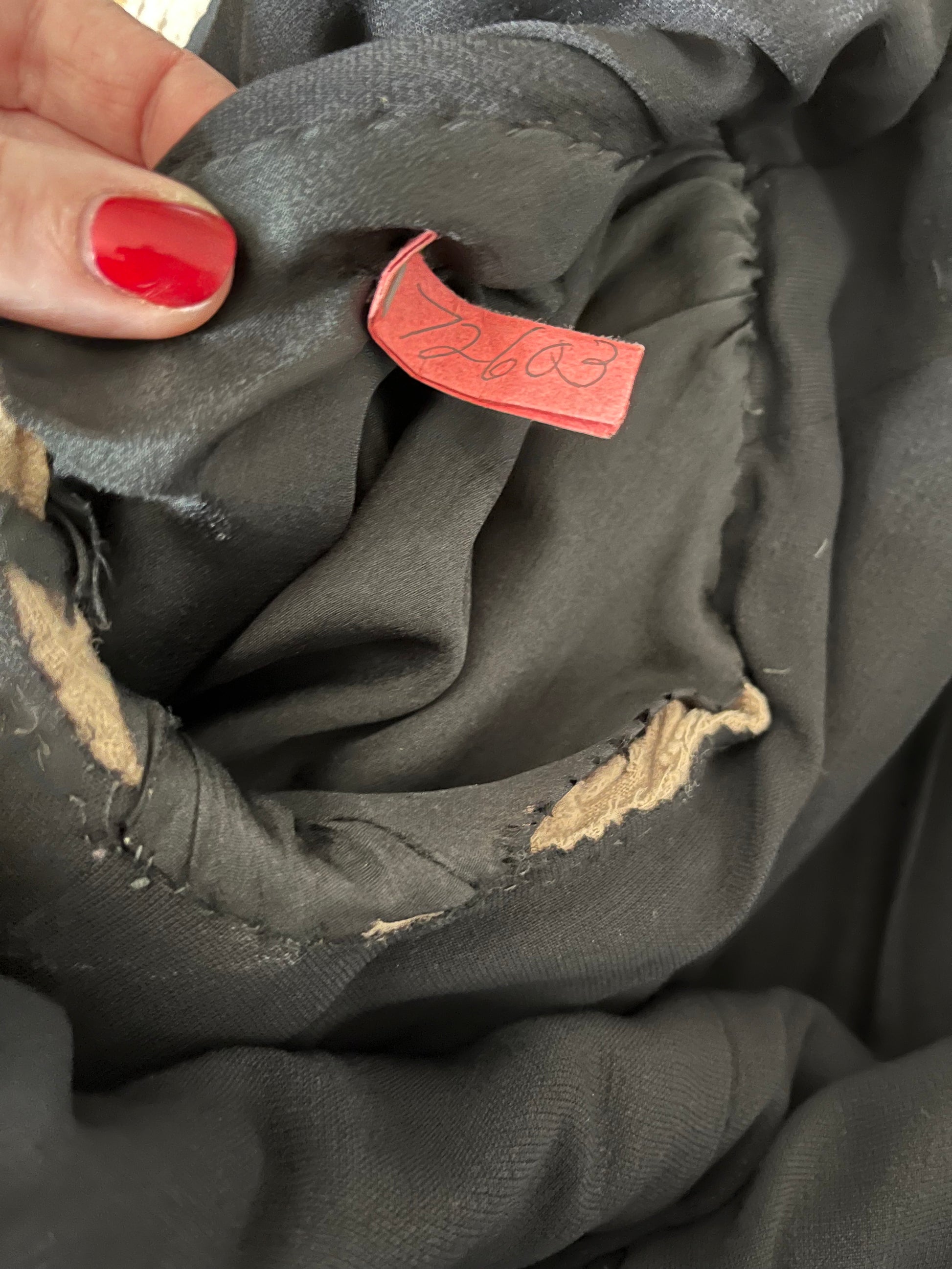Close up of tag at interior of arm hole, reads "72603".  Also shows damage at lining .